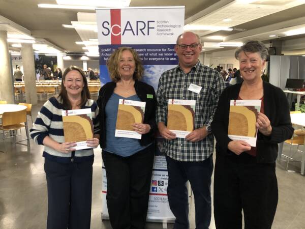 Photo of four people holding the newly published book of the ScARF Dendrochronology Research Framework for Scotland